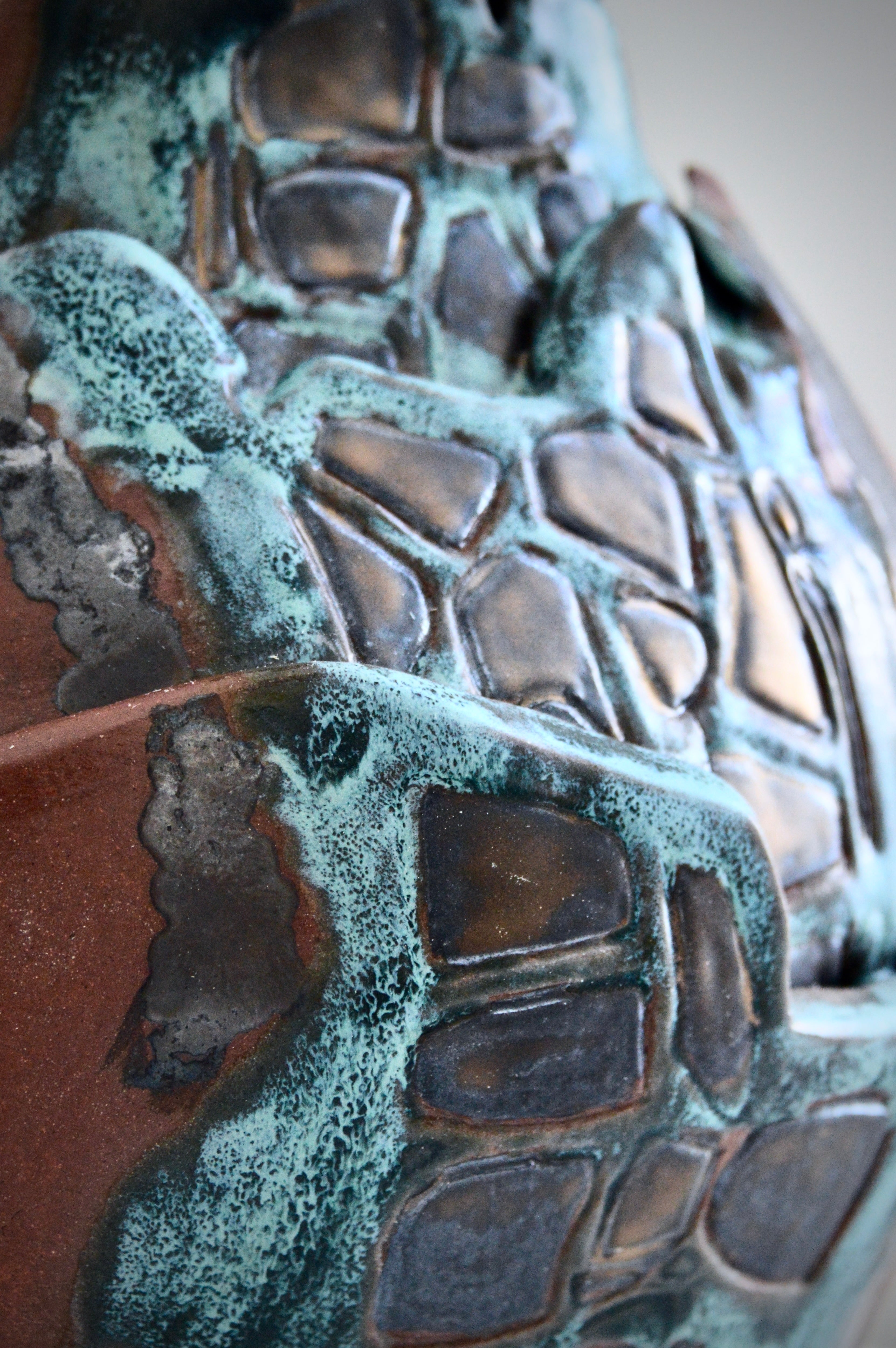 Close-up of a textured ceramic vase surface with greenish patina
