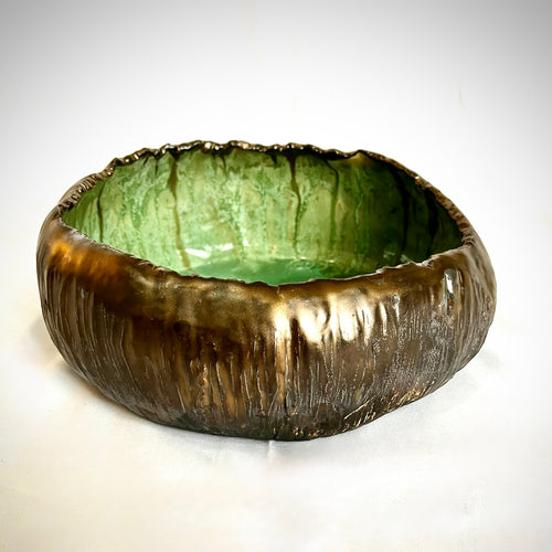 Ceramic bowl with glossy green interior and brown exterior on a white background