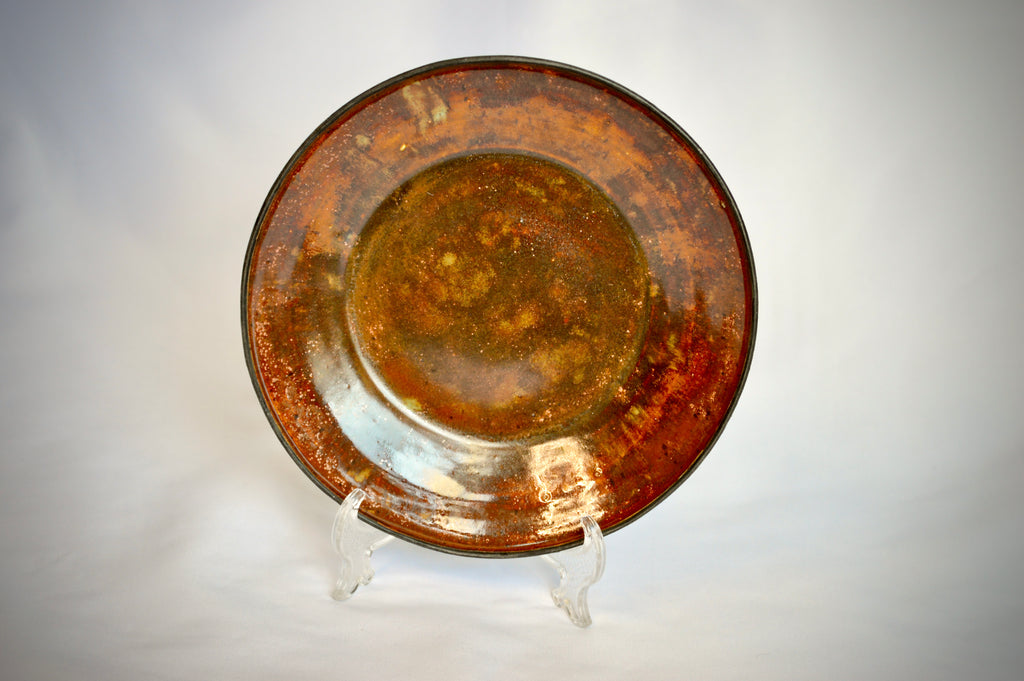 Rust-colored ceramic plate on a stand against a light gray background