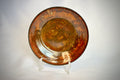 Rust-colored ceramic plate on a stand against a light gray background