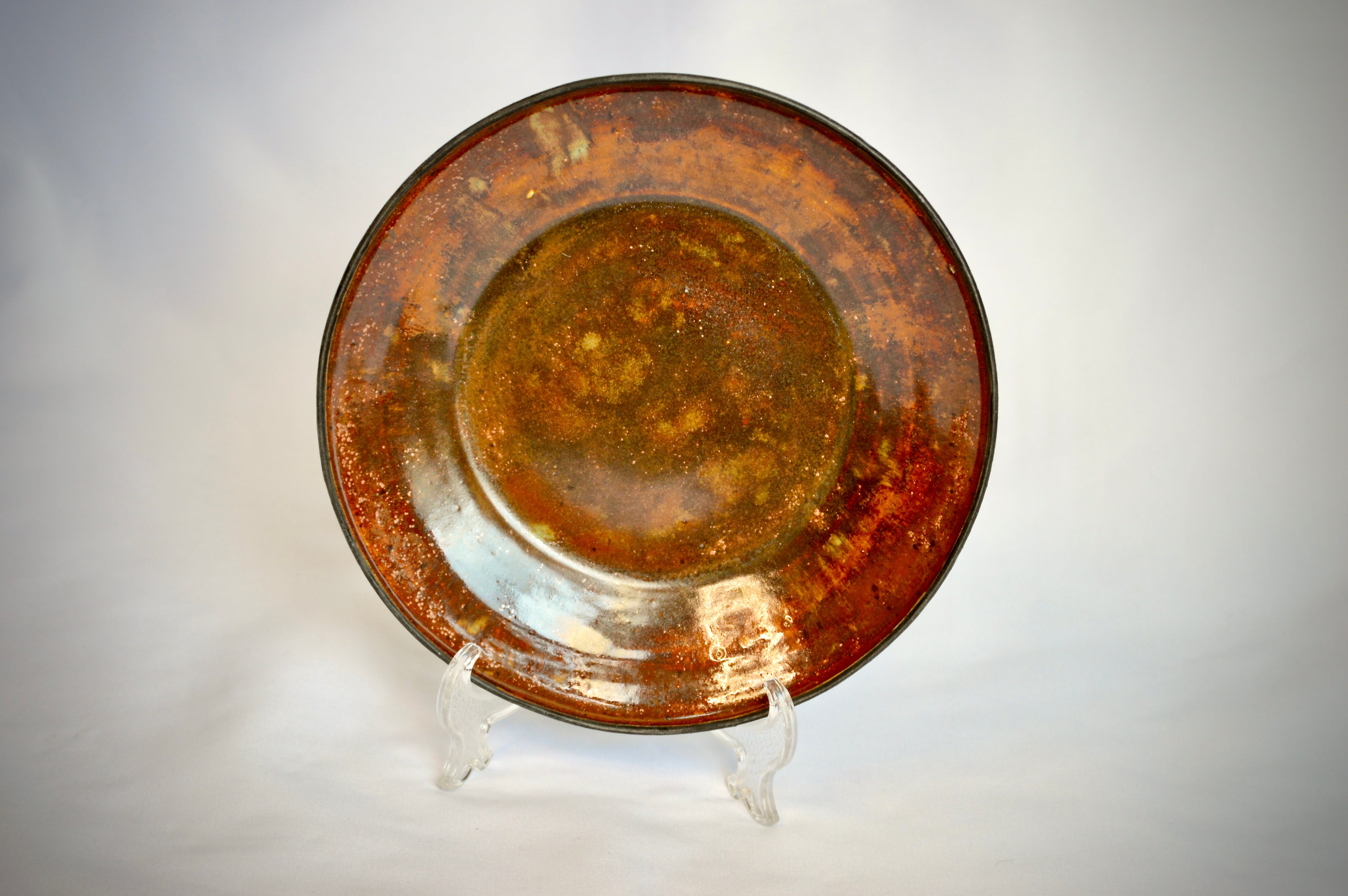 Rust-colored ceramic plate on a stand against a light gray background