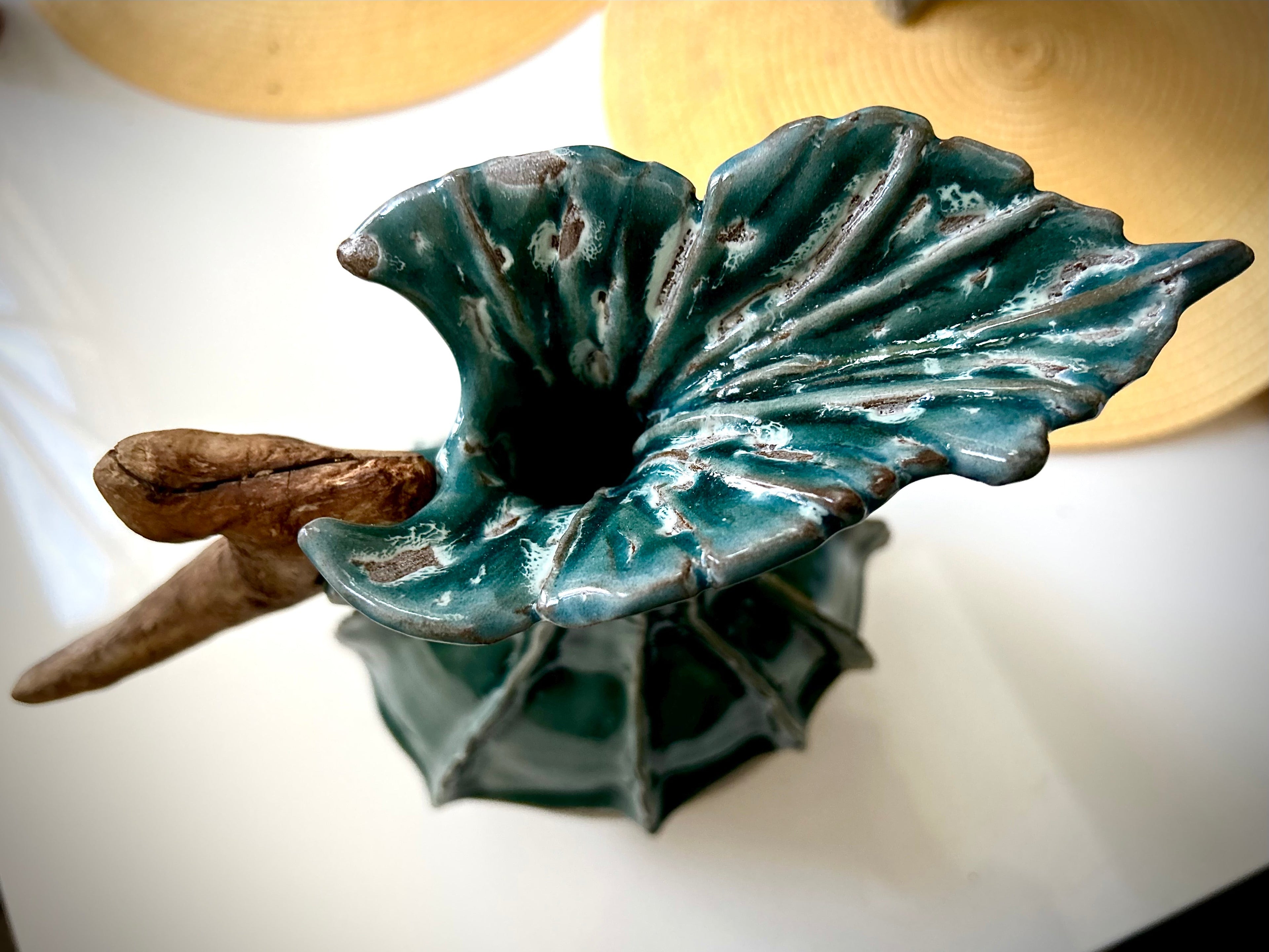 Teal ceramic leaf-shaped top of a sculpture on a white surface