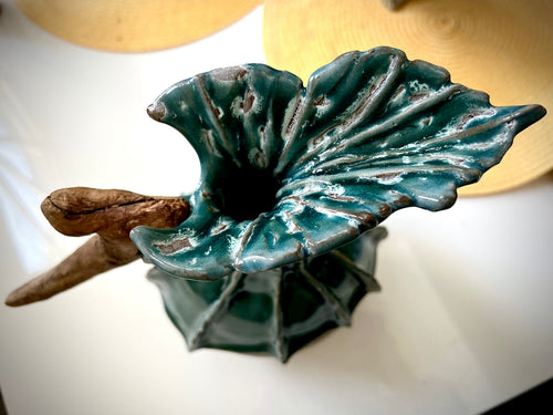 Teal ceramic leaf-shaped top of a sculpture on a white surface