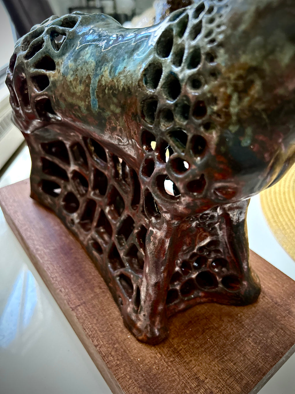 Closeup ceramic sculpture of a horse with textured surface on a wooden base