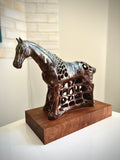 Bronze horse sculpture on a wooden base against a neutral background