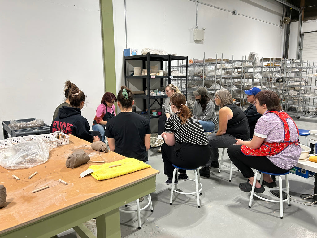 Group of people in a workshop setting with Sowgand Nabipour with tools and materials on tables.