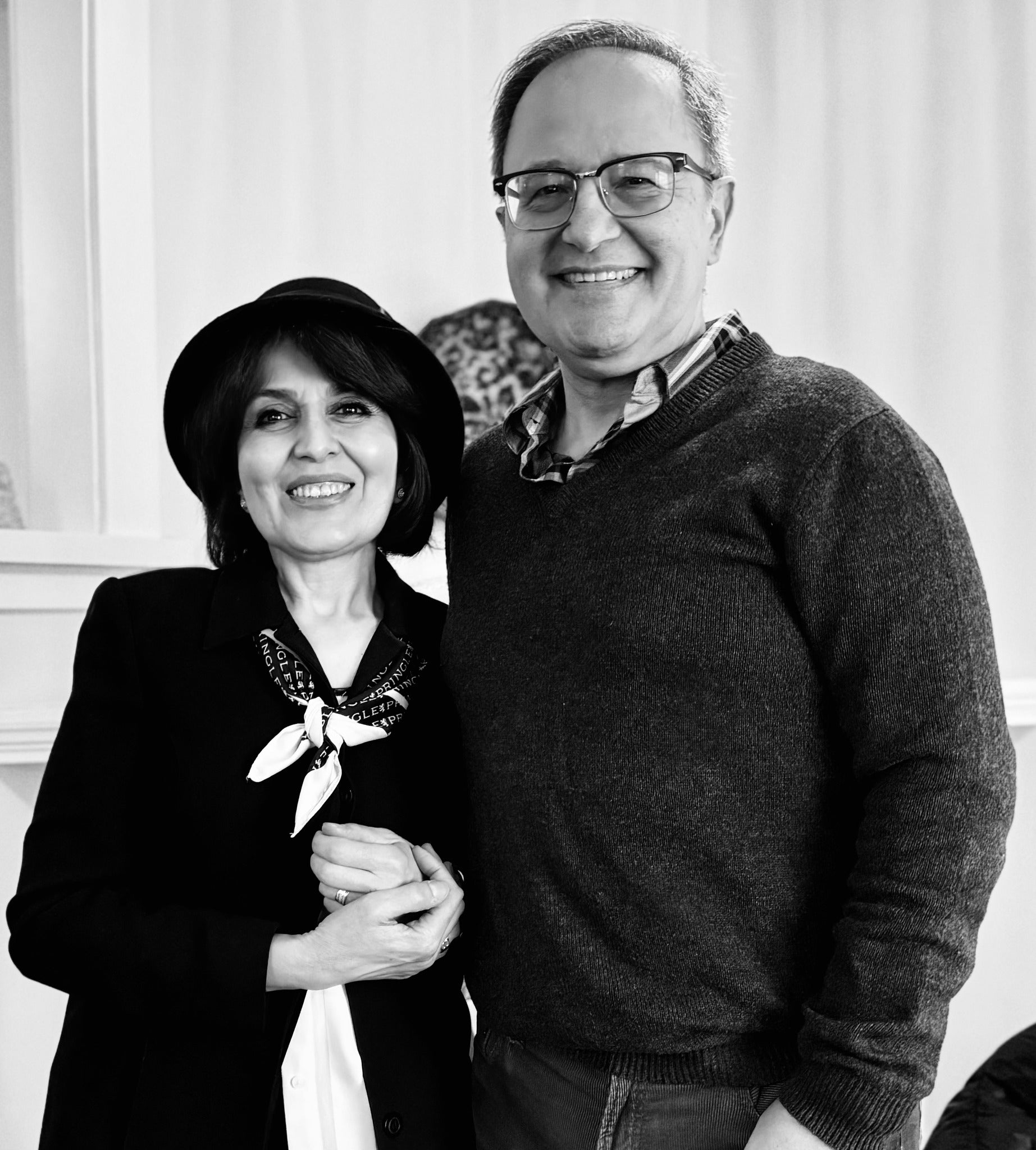 Black and white photo of a man and woman posing together indoors. Sowgand and Kiumars.