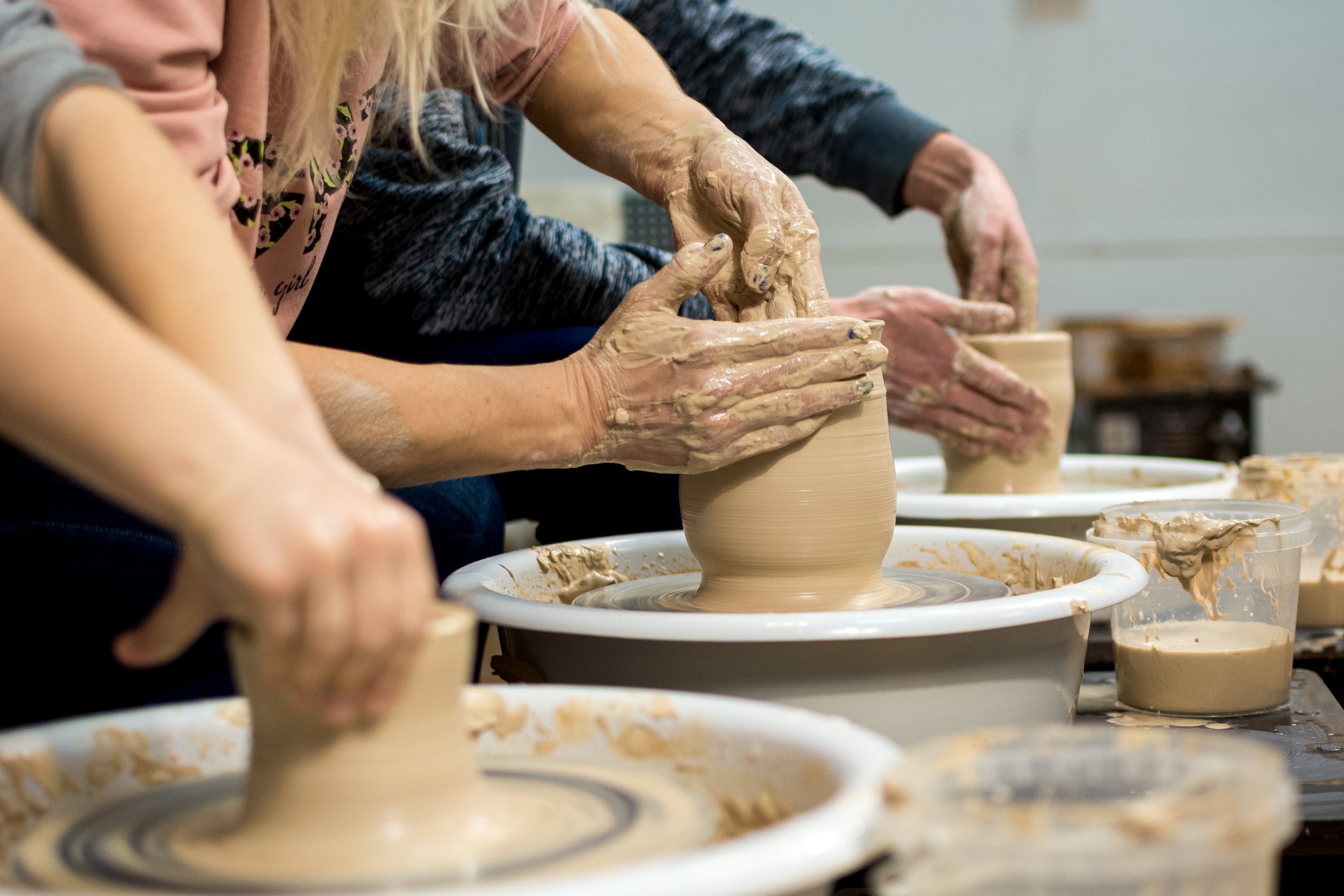 Three people working on pottery in a studio setting.