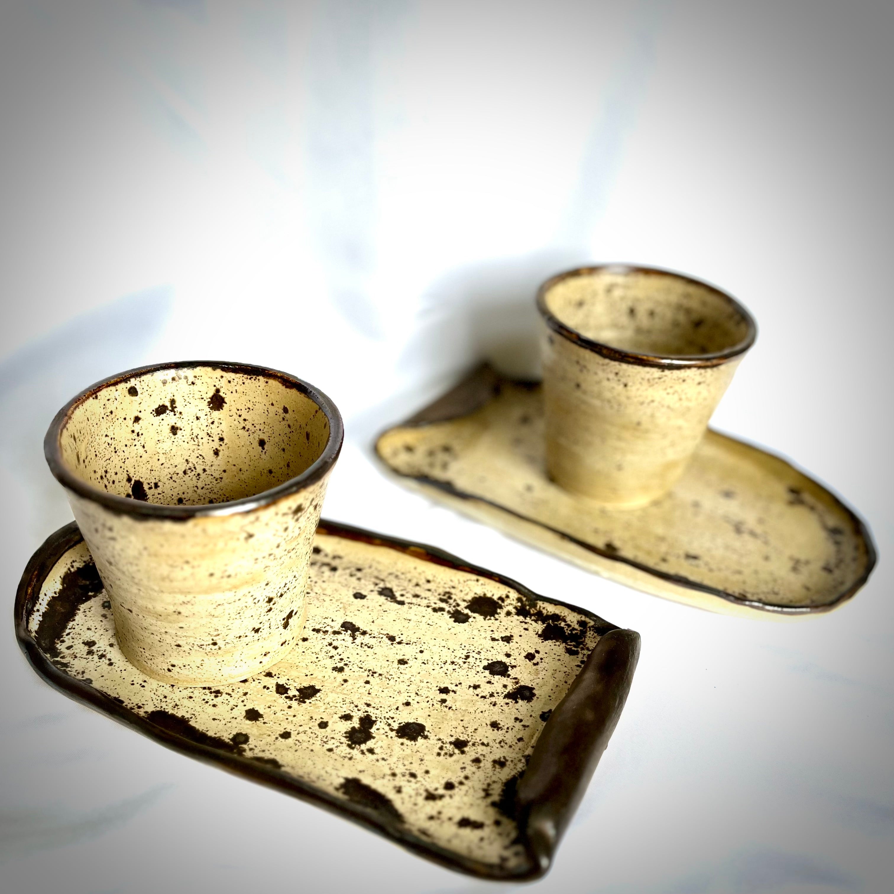 Speckled ceramic tray with two cups on a white background